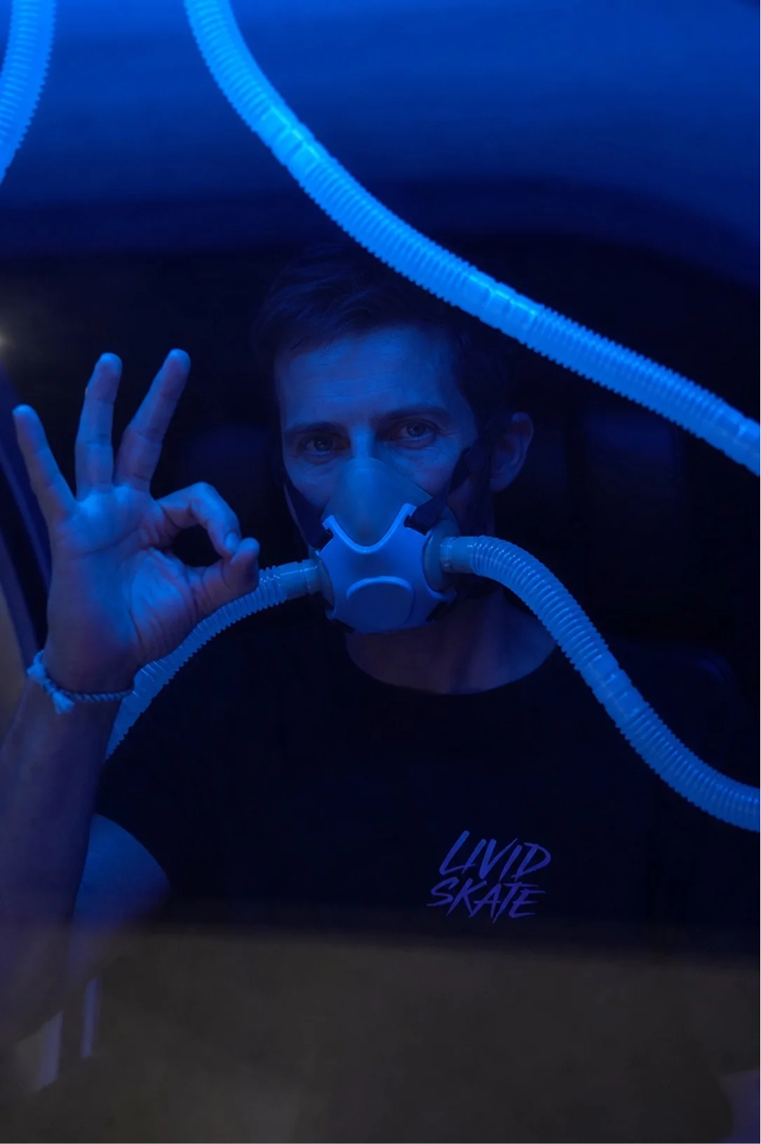 A guest on the oxygen mask inside a chamber partway through a session